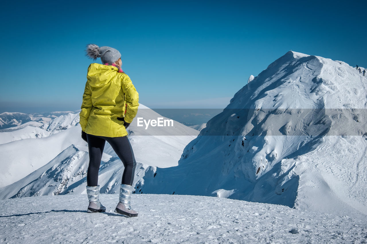 Rear view of woman standing on snowcapped mountain