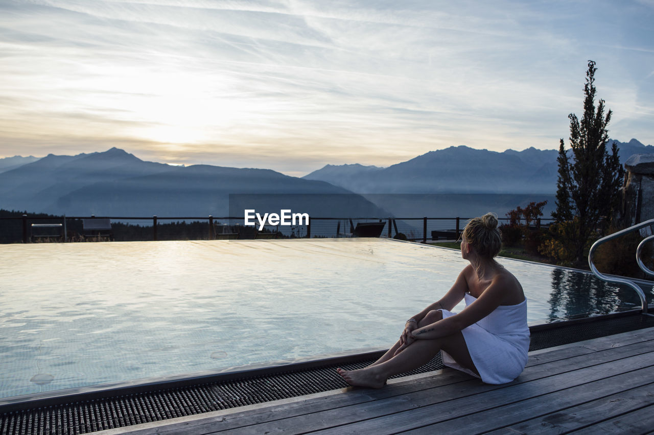 Woman relaxing at the poolside, wrapped in towel