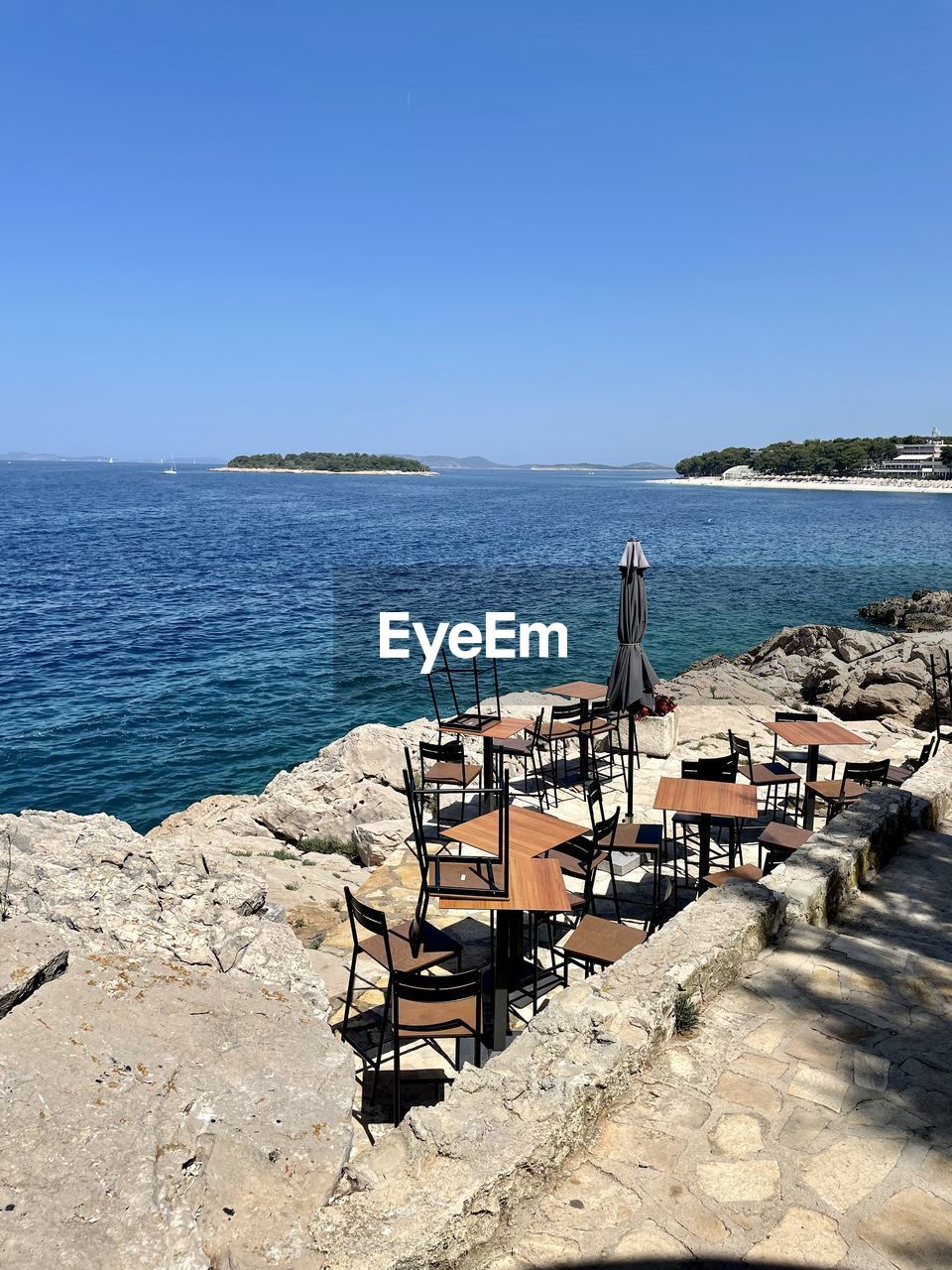 water, sea, sky, shore, vacation, ocean, coast, nature, clear sky, beach, land, bay, scenics - nature, body of water, sunny, sunlight, day, blue, tranquility, beauty in nature, travel destinations, chair, architecture, horizon, horizon over water, tranquil scene, no people, seat, travel, copy space, outdoors, trip, holiday, coastline, built structure, summer, tourism, sand, rock, idyllic, cove, pier