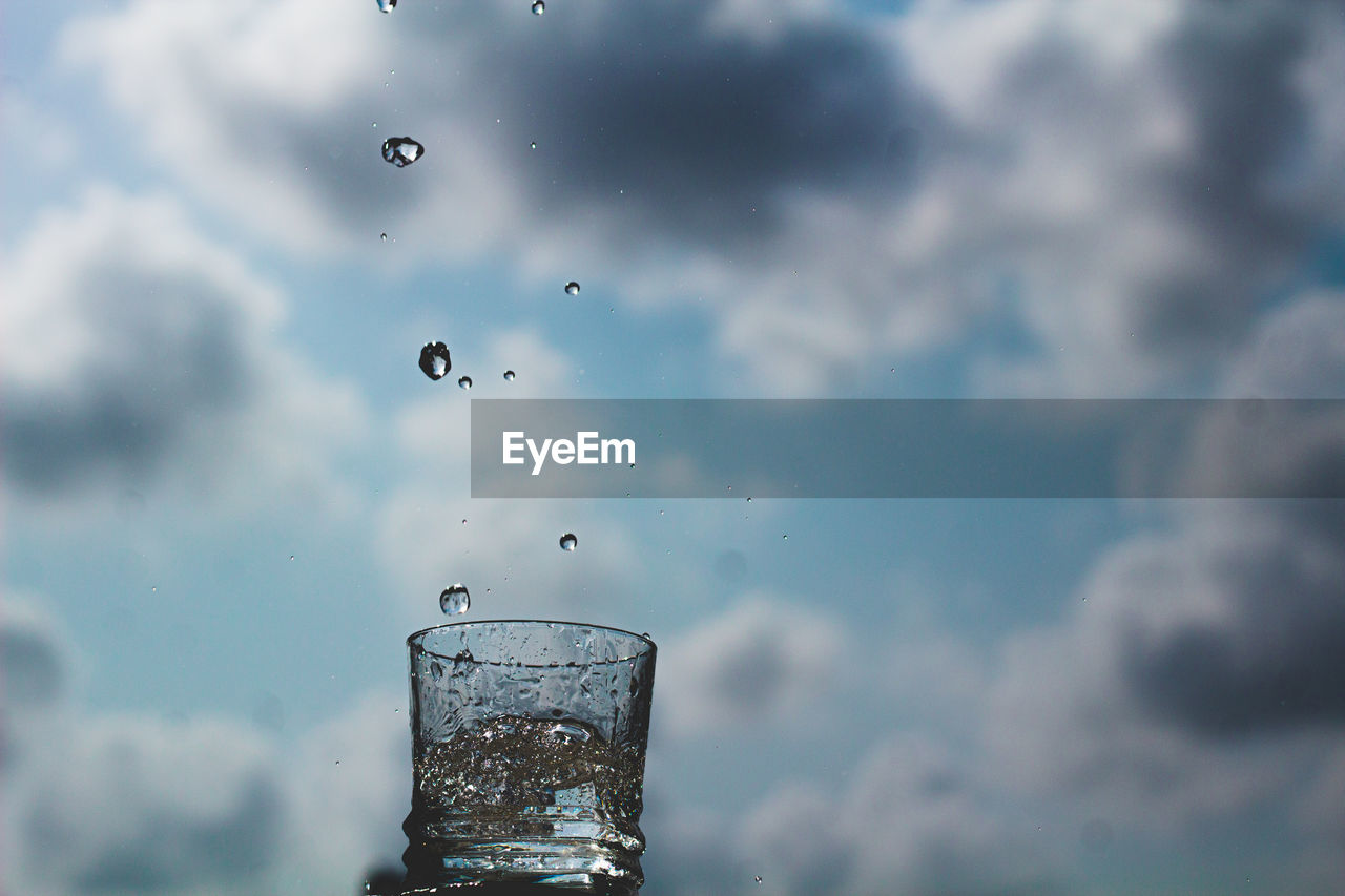 Close-up of water drops on glass against the sky