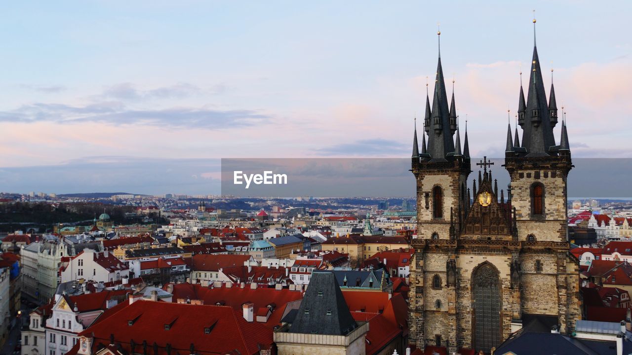 Tyn church amidst buildings against sky at dusk