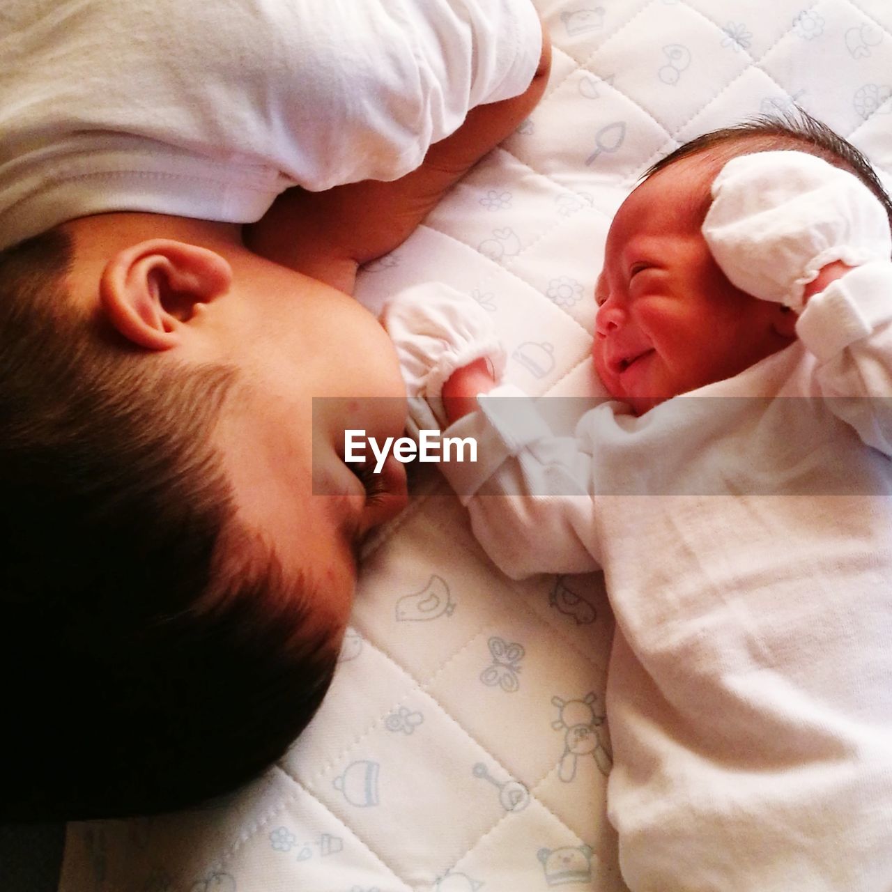High angle view of siblings lying down on bed at home