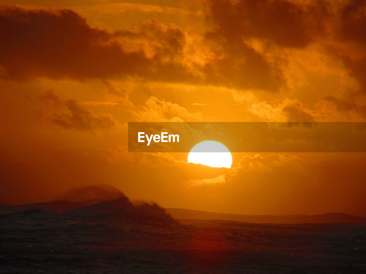 Scenic view of sea against dramatic sky during sunset