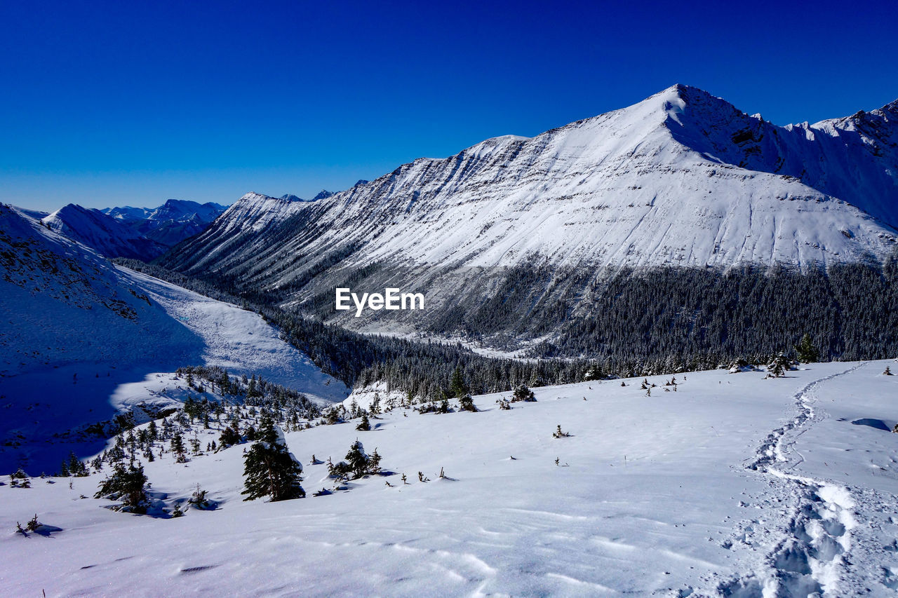 Scenic view of snowcapped mountains against clear blue sky