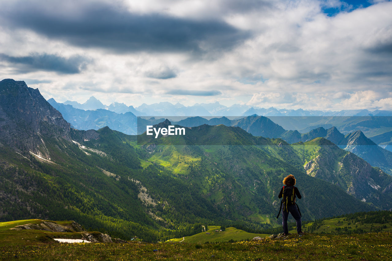 Rear view of man standing on mountain against sky