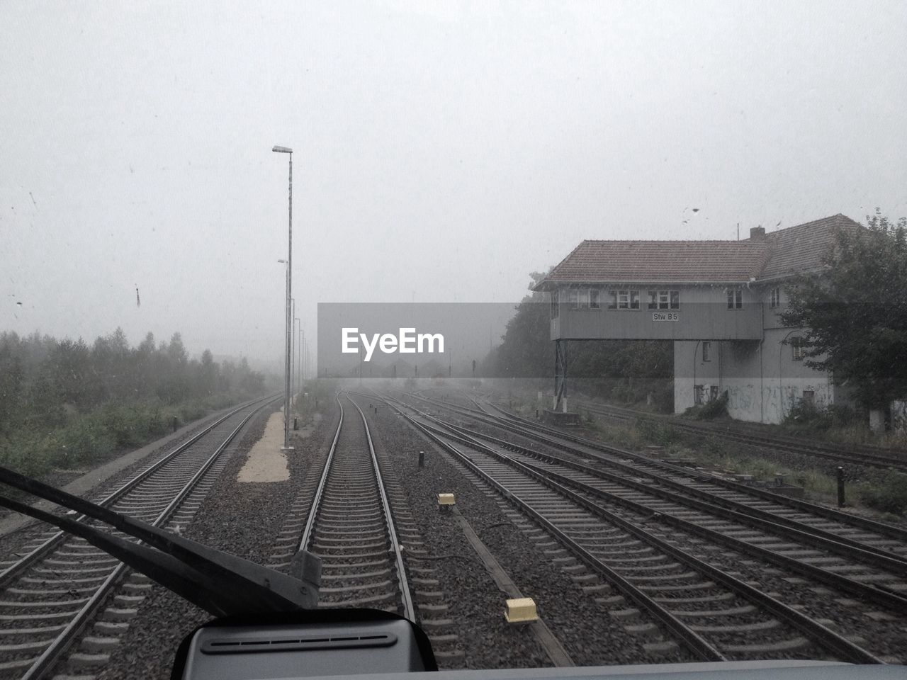 Railroad tracks seen through windshield against clear sky