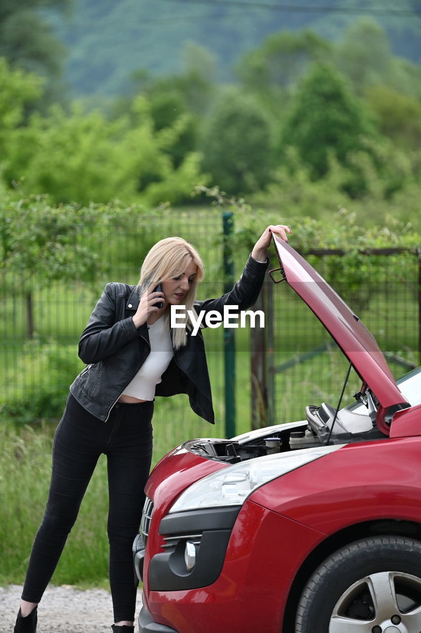 Young woman on phone looking at engine 