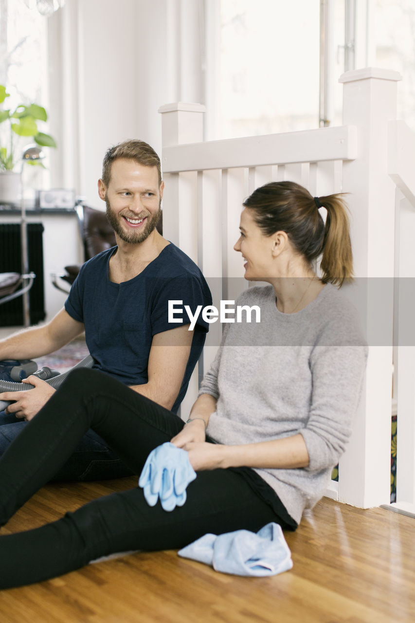 Happy couple looking at each other while sitting on hardwood floor