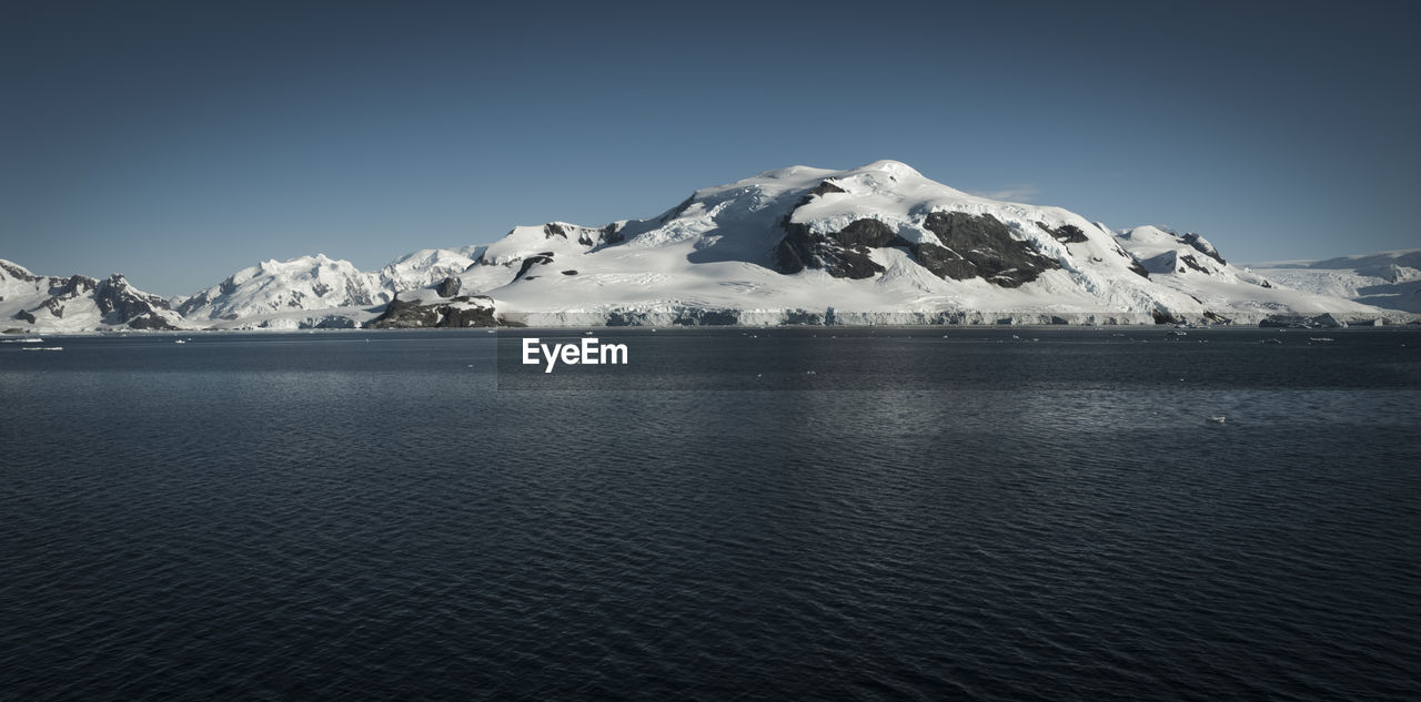 scenic view of sea against snowcapped mountains