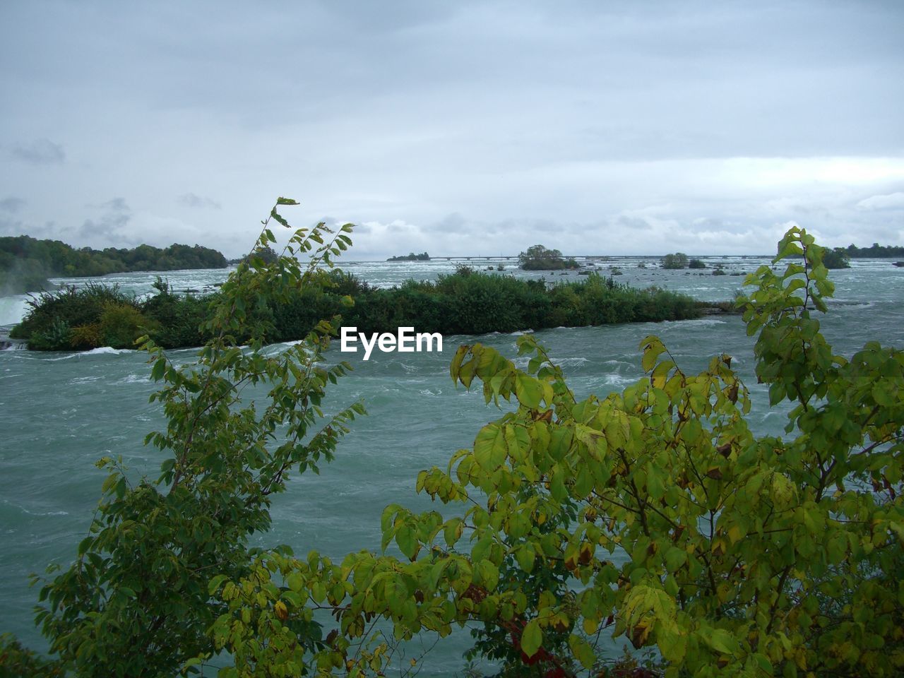 Scenic view of river against cloudy sky