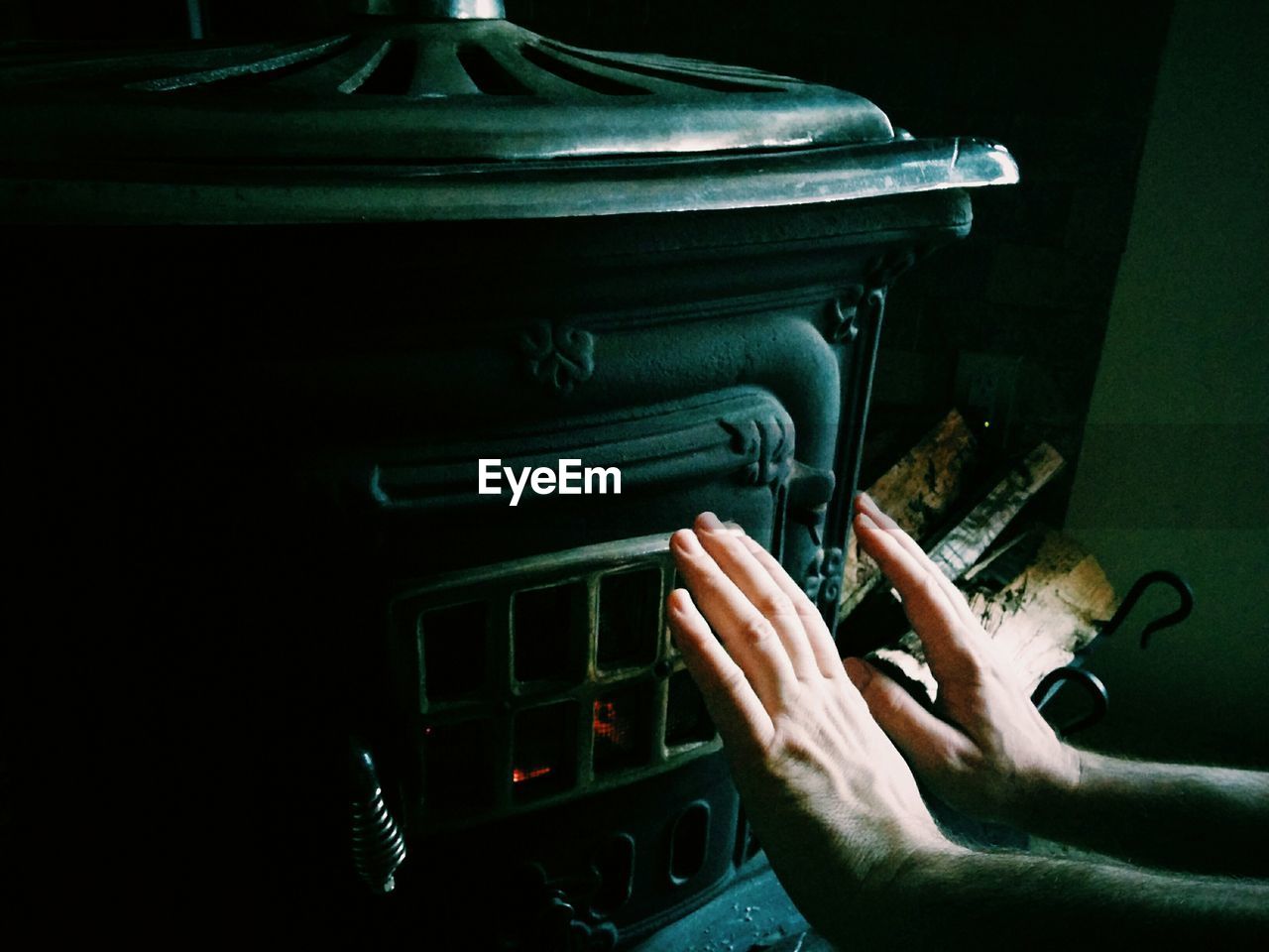 Close-up of hands warming by fireplace during winter