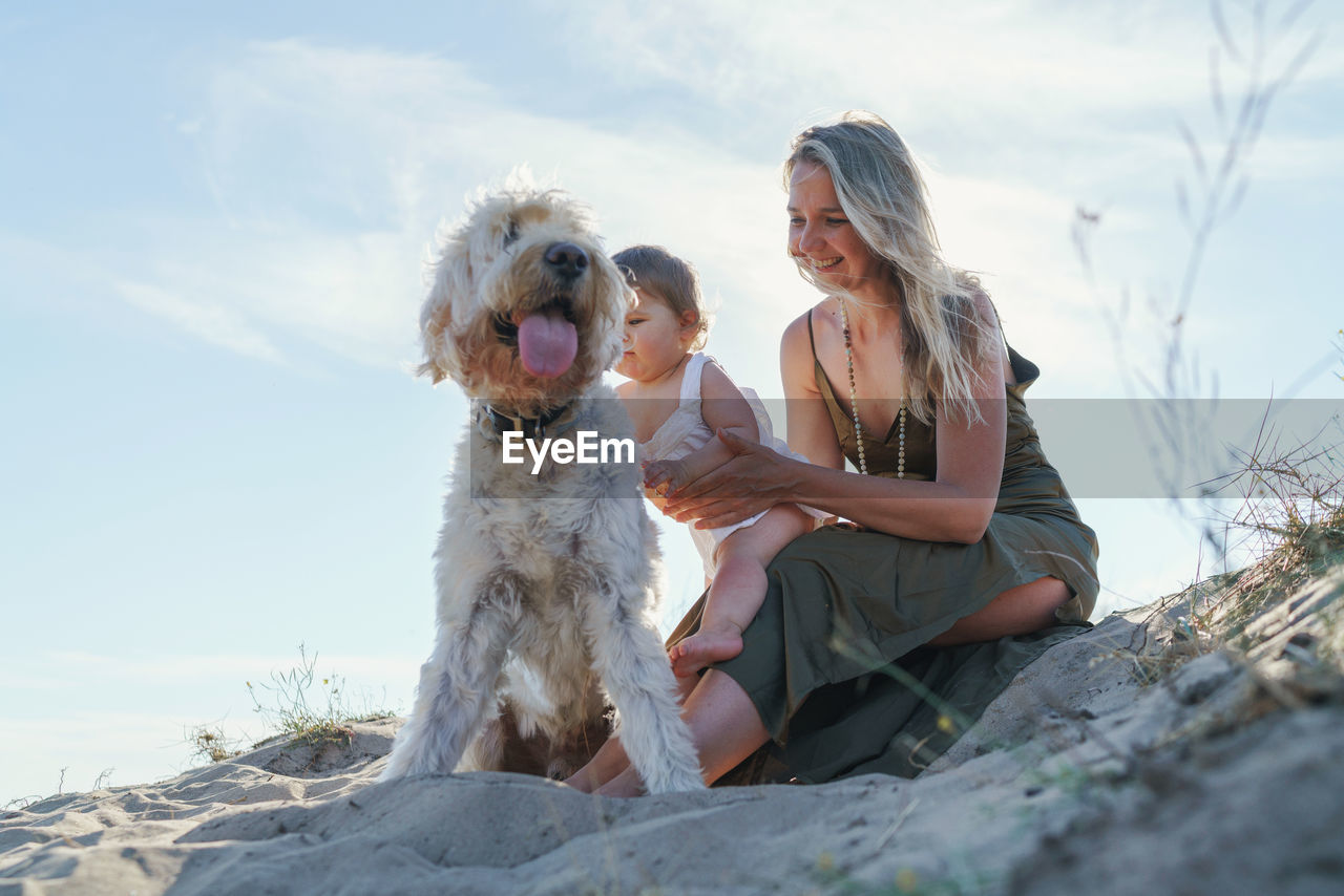 Woman and child  with dog sitting against sky