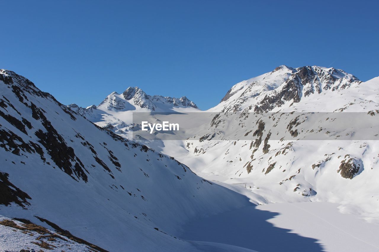 Scenic view of snowcapped mountains against clear blue sky