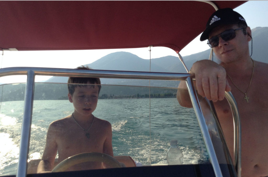 PORTRAIT OF SHIRTLESS MAN SITTING IN BOAT