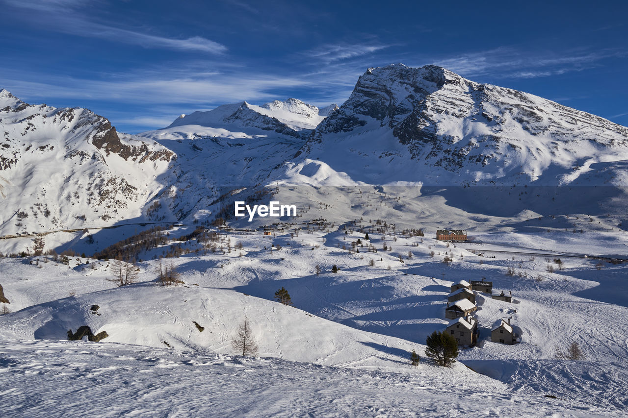 Scenic view of houses on snow covered land against sky