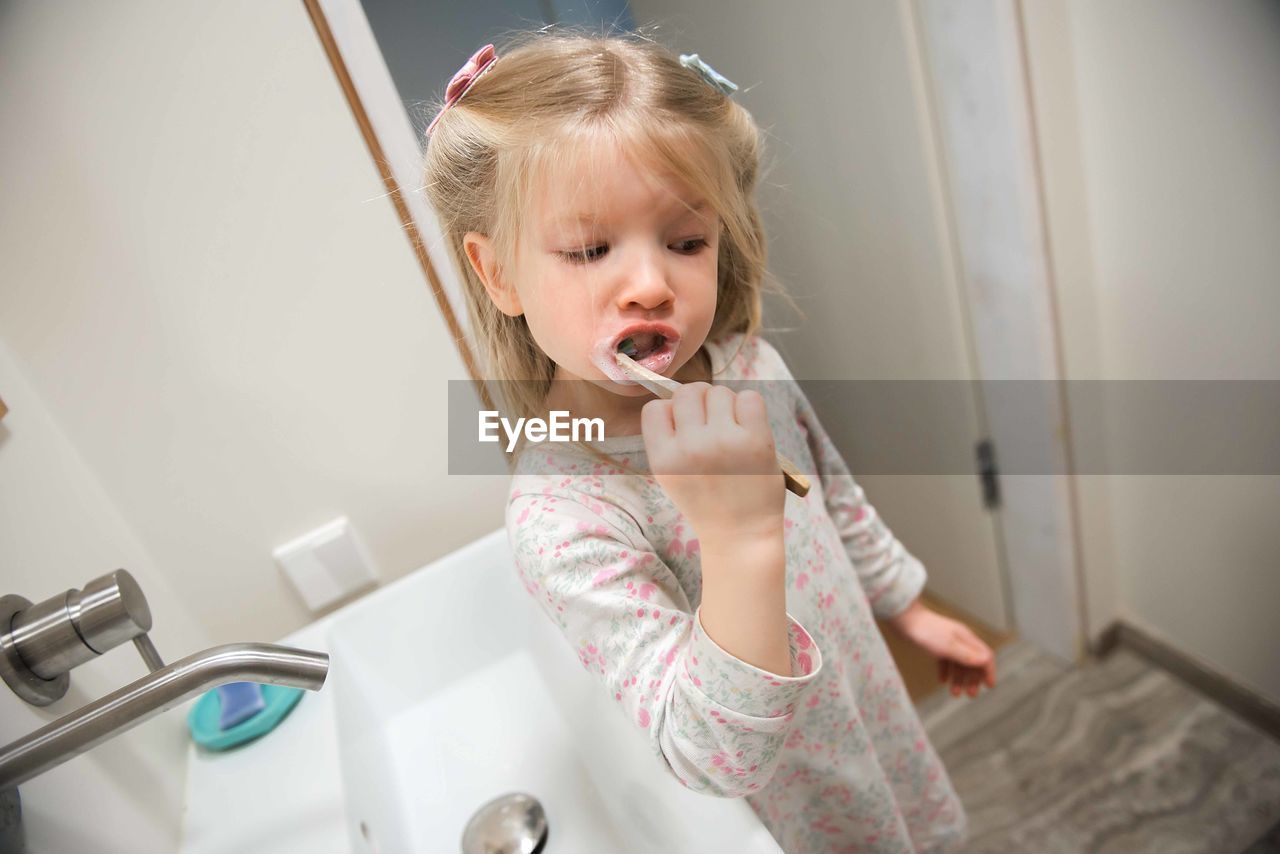 Girl brushing teeth in bathroom at home