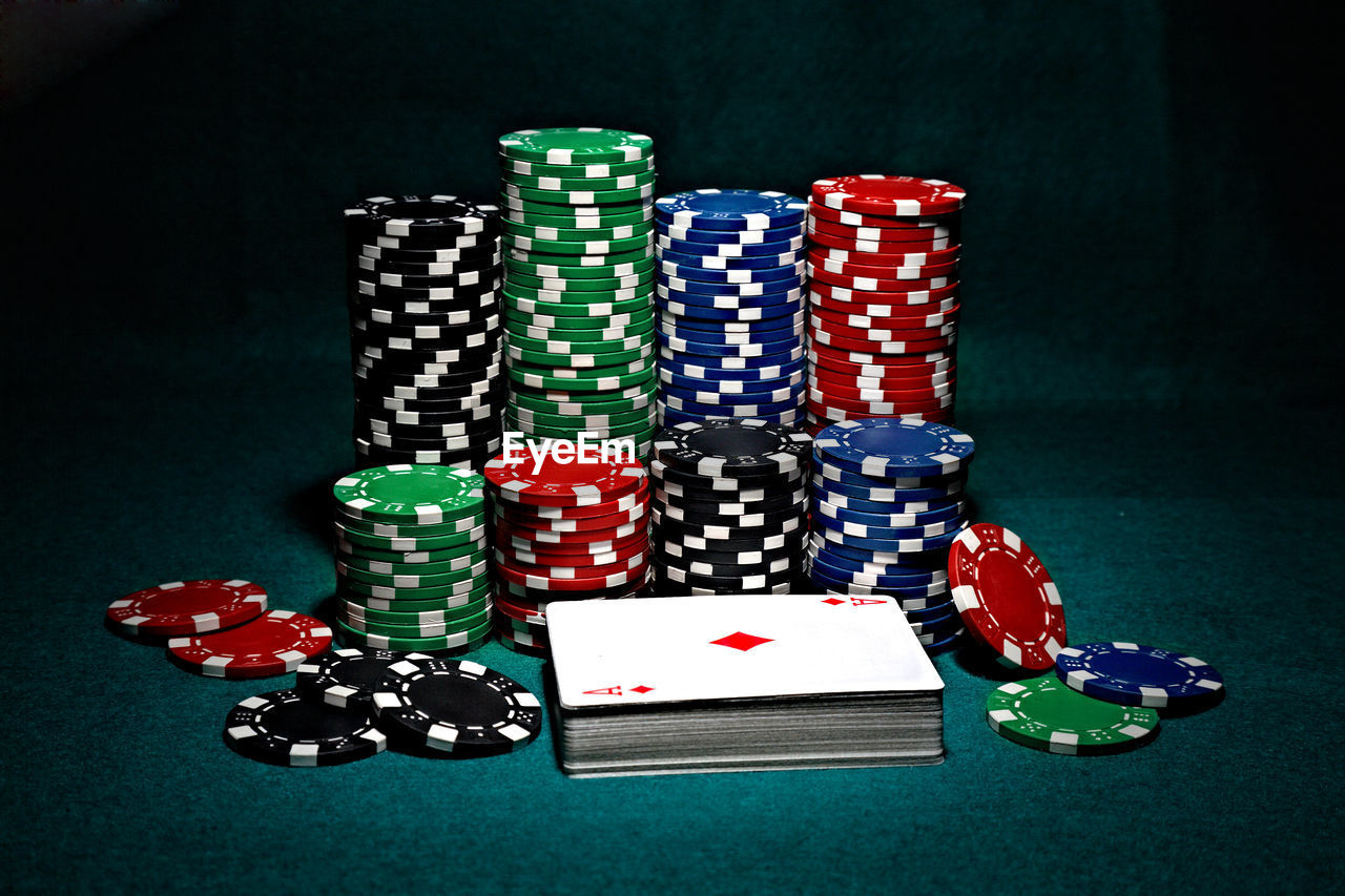 Stack of multi colored gambling chips on table against black background