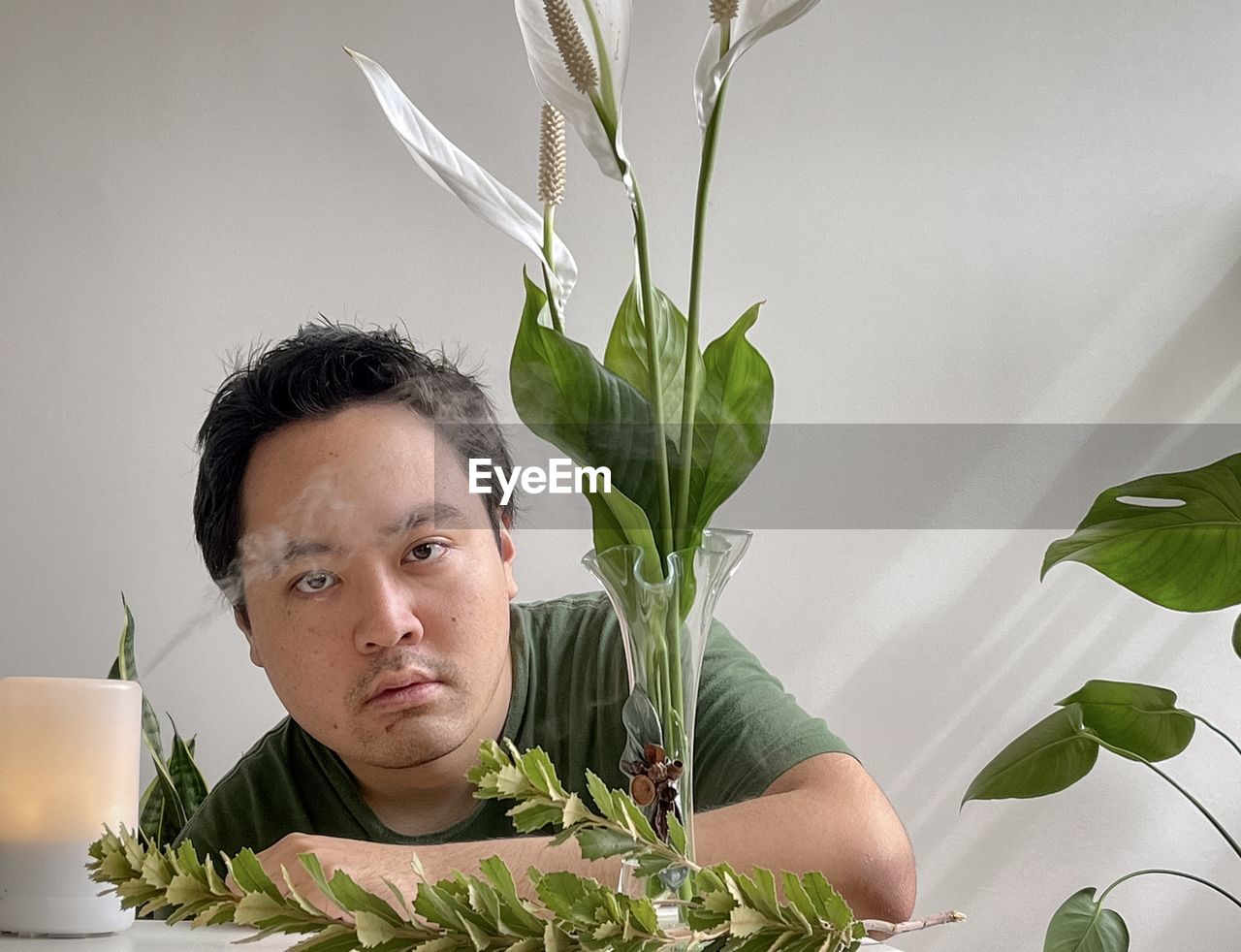 Portrait of asian man with aromatherapy diffuser, peace lilies in vase and plants.