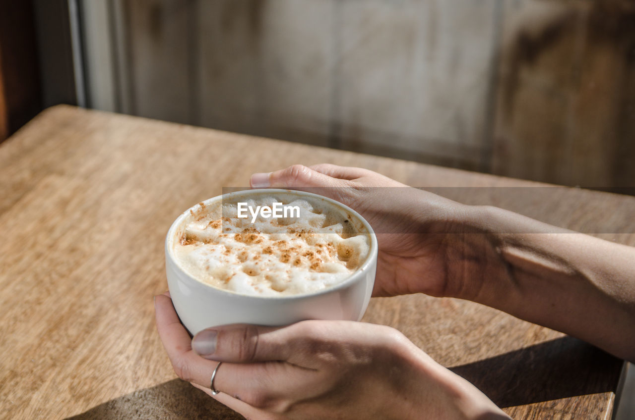 Cropped hand of businesswoman holding coffee in cafe