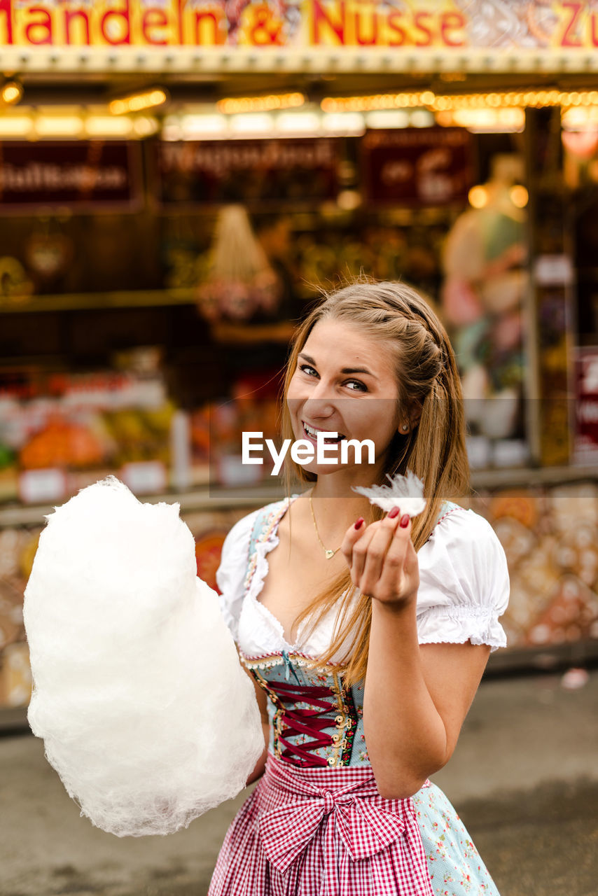 Portrait of happy woman eating cotton candy at oktoberfest