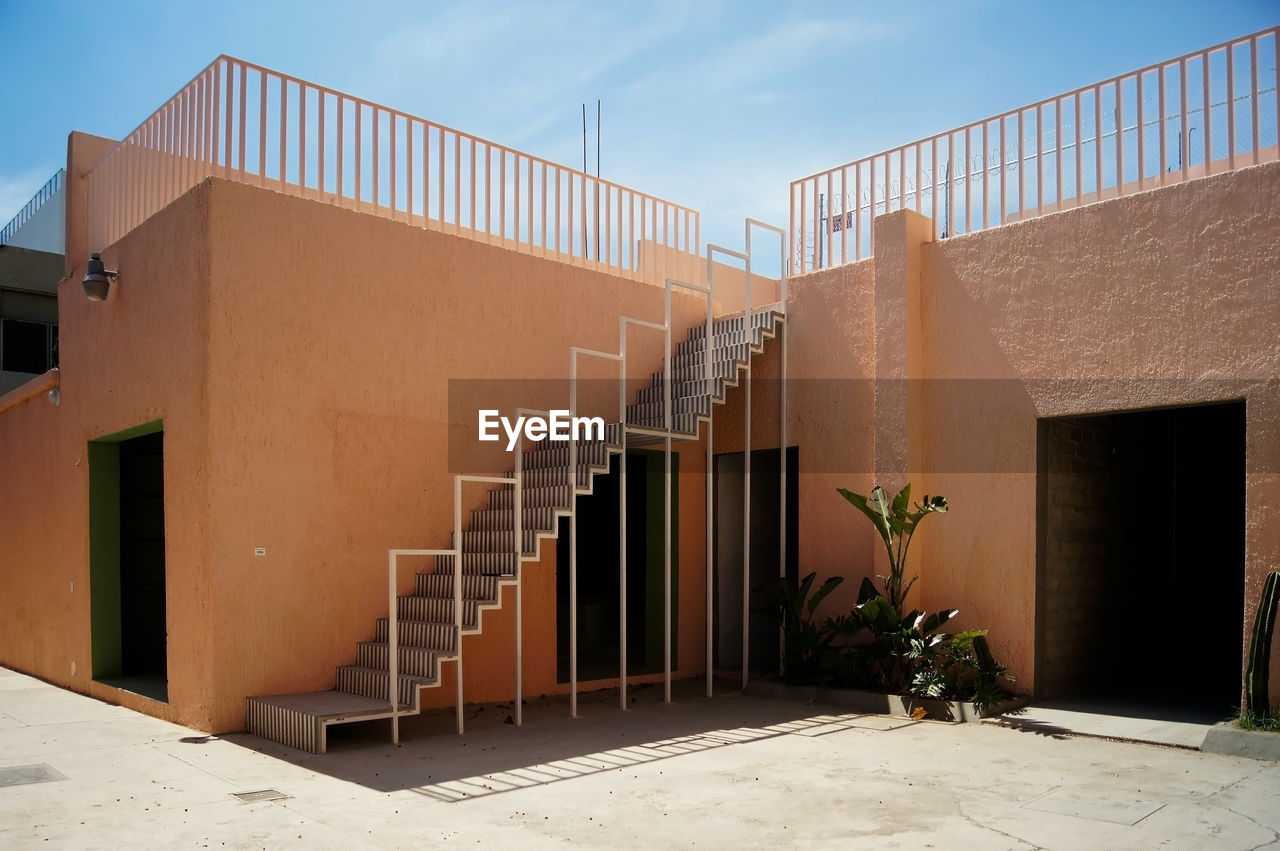 Regionalist house, painted pink with white ironwork staircase, a handrail is visible at the top