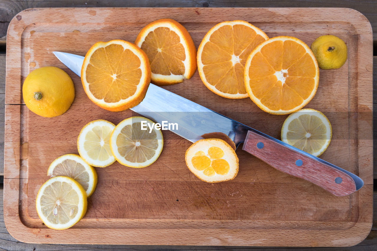Close-up of citrus fruits with kitchen knife on cutting board