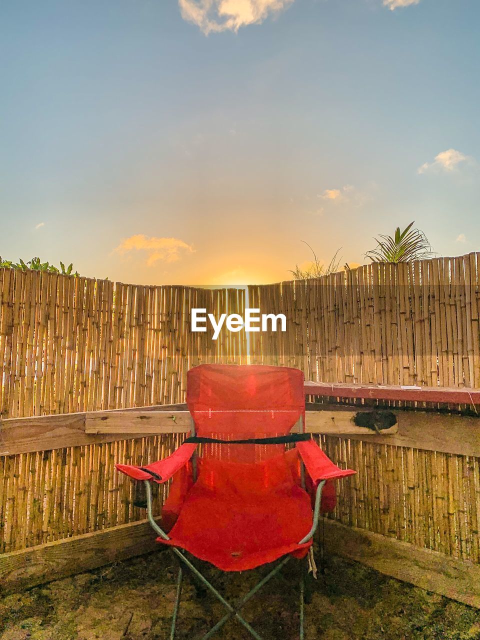 EMPTY CHAIRS AGAINST ORANGE SKY DURING SUNSET