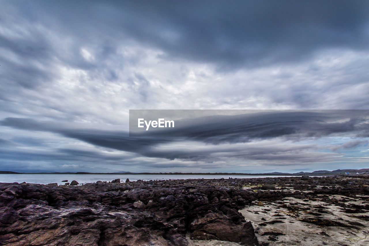 SCENIC VIEW OF BEACH AGAINST CLOUDY SKY