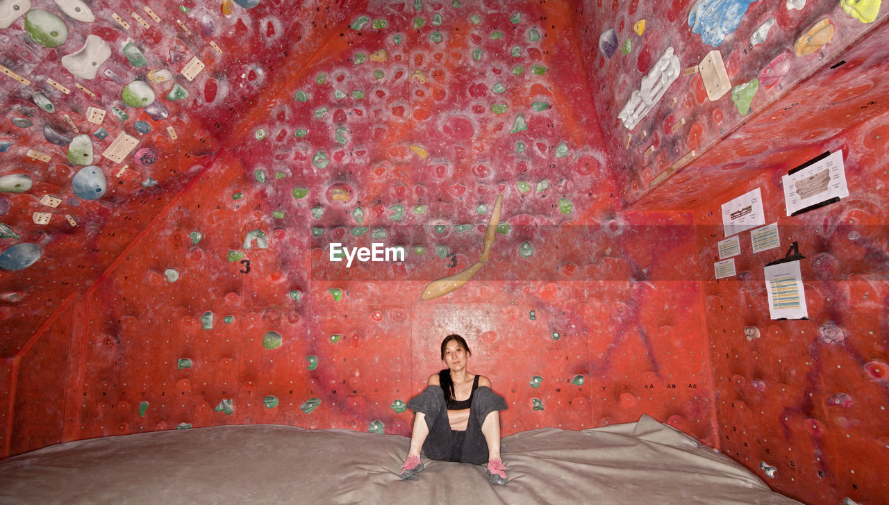 Woman resting on bouldering mat at indoor climbing gym