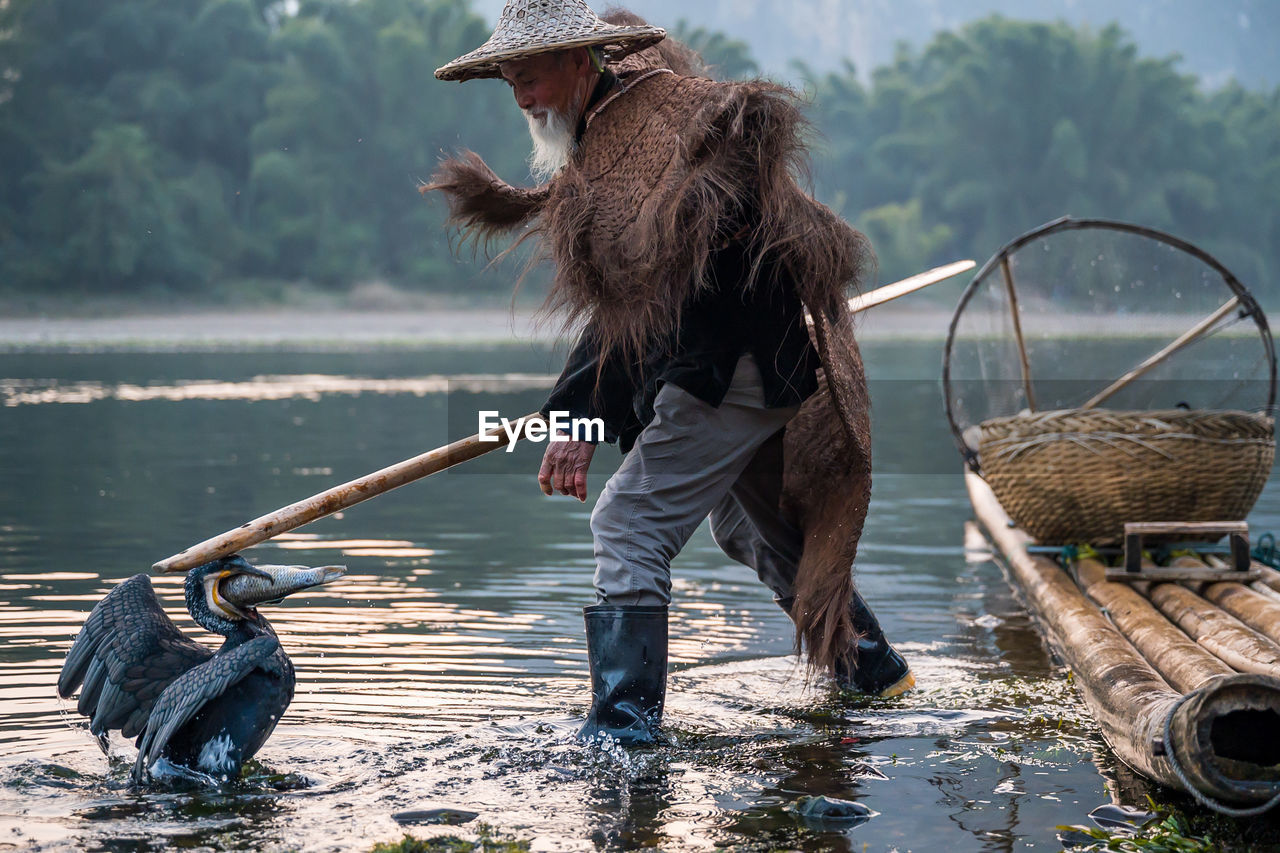 Man with bird fishing in lake