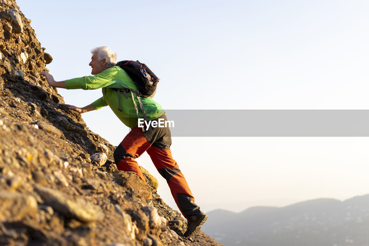 Senior man hiking a mountain during sunny day