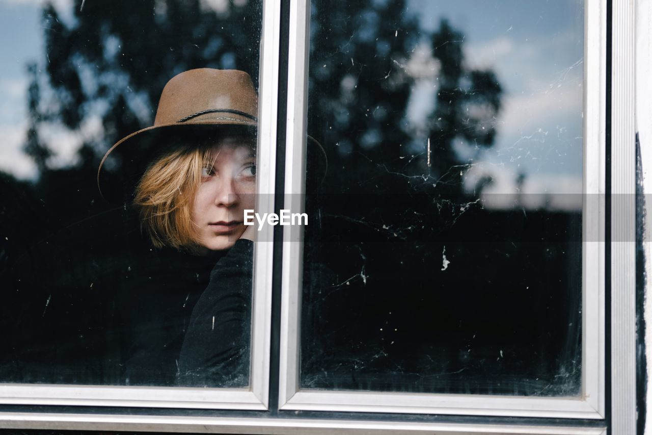 Modern girl with a hat looking trough the window, female outdoor portrai