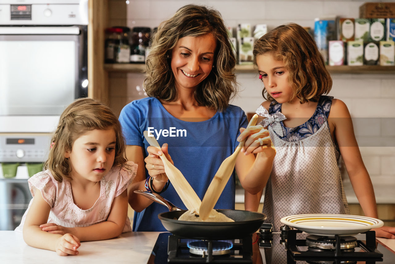 Mother and daughters preparing food in kitchen at home