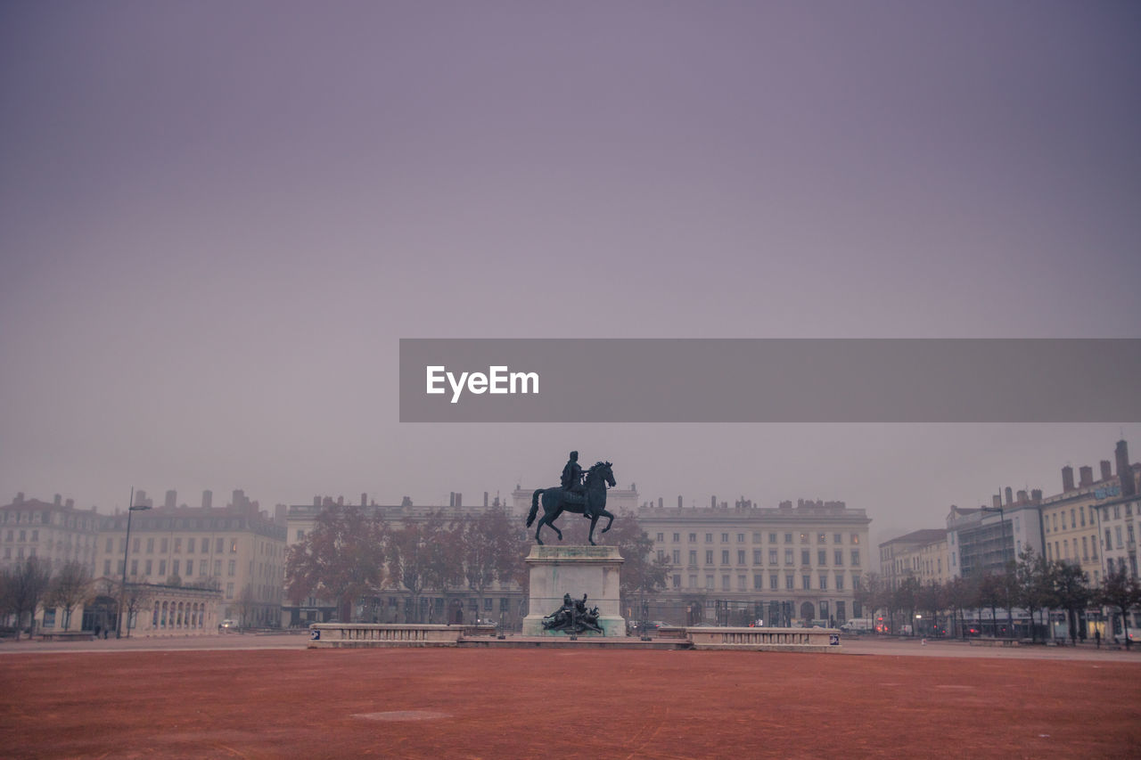 Statue and bellecour square in city against clear sky at the morning