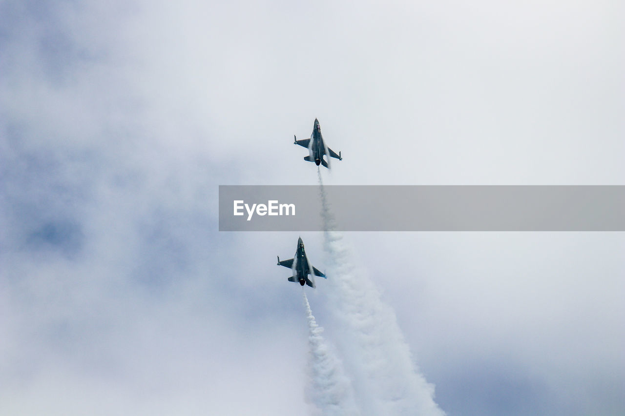 Low angle view of airshow against cloudy sky
