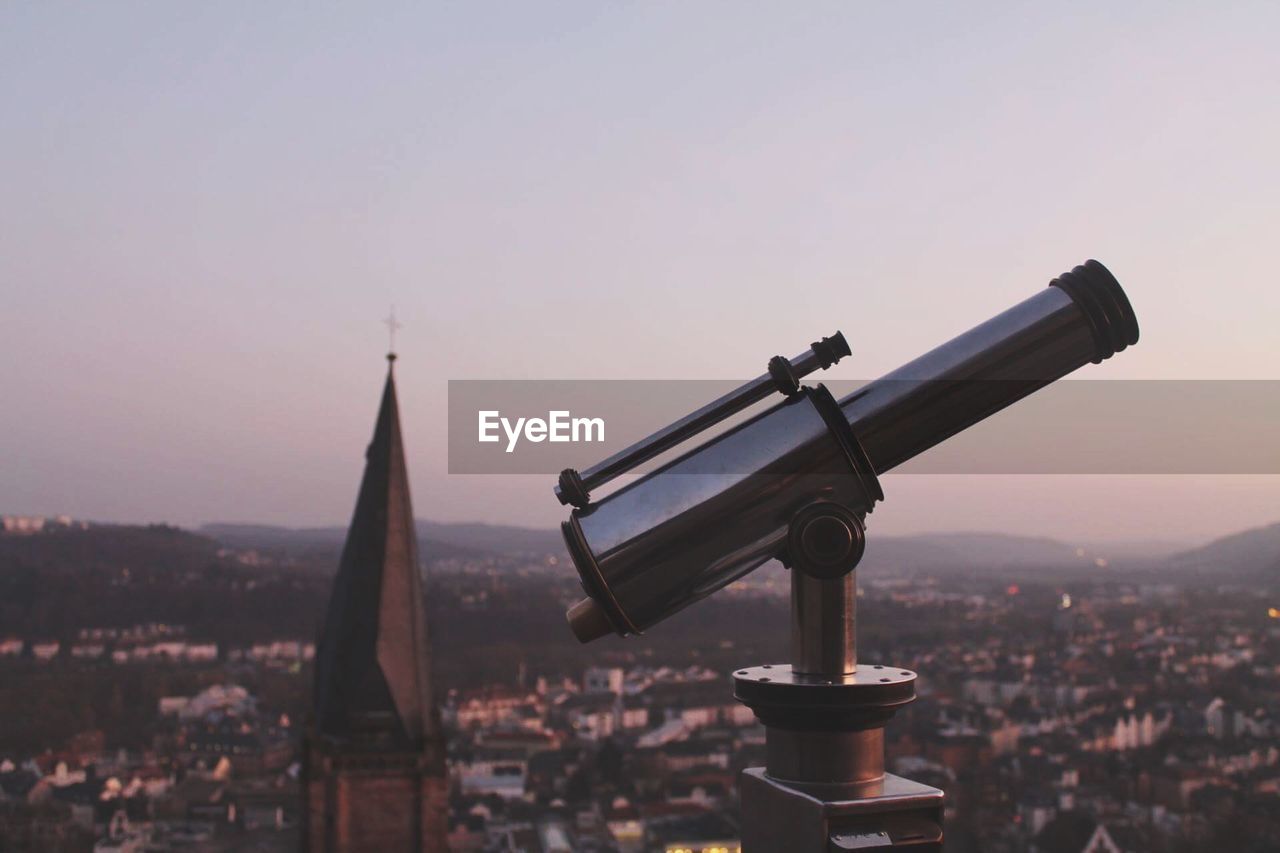 Coin-operated binoculars in city against sky