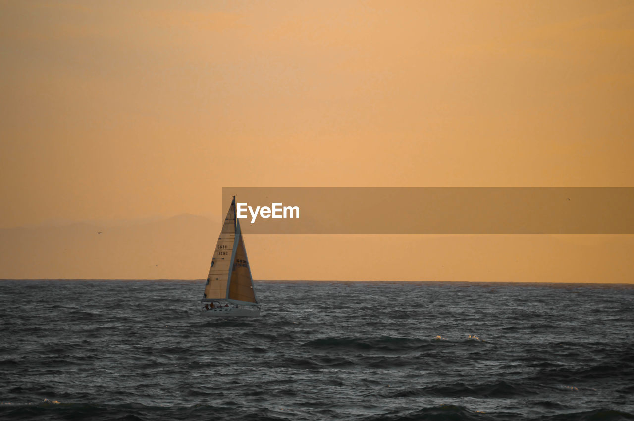 Boat sailing on sea against clear sky during sunset