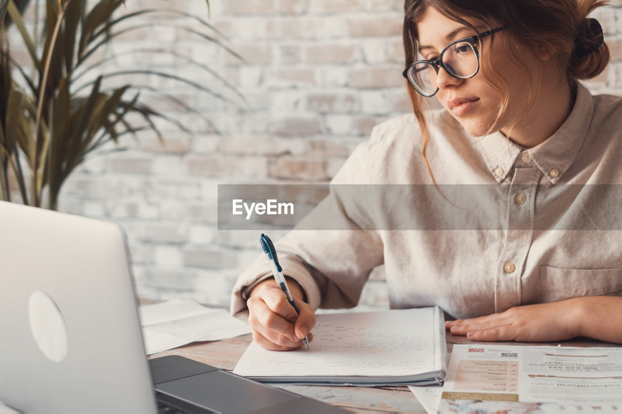 young woman using mobile phone on table at home