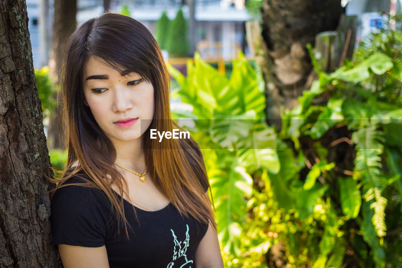 PORTRAIT OF BEAUTIFUL YOUNG WOMAN WITH TREE