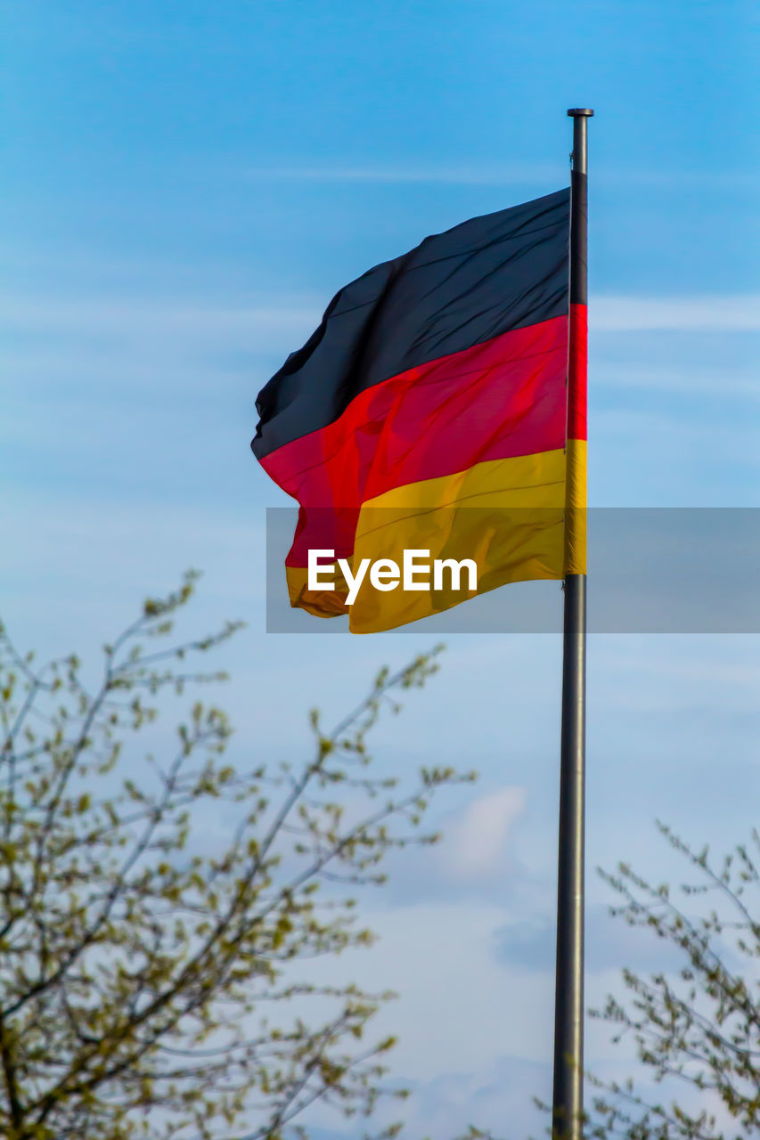 Federal republic of germany, german national flag waving on the blue sky background, de