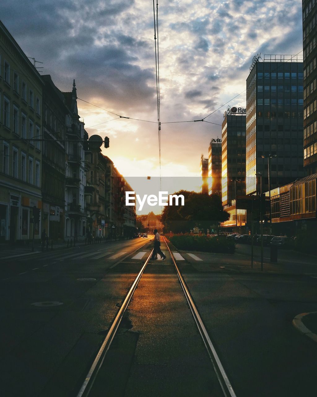 City street amidst buildings against cloudy sky during sunset