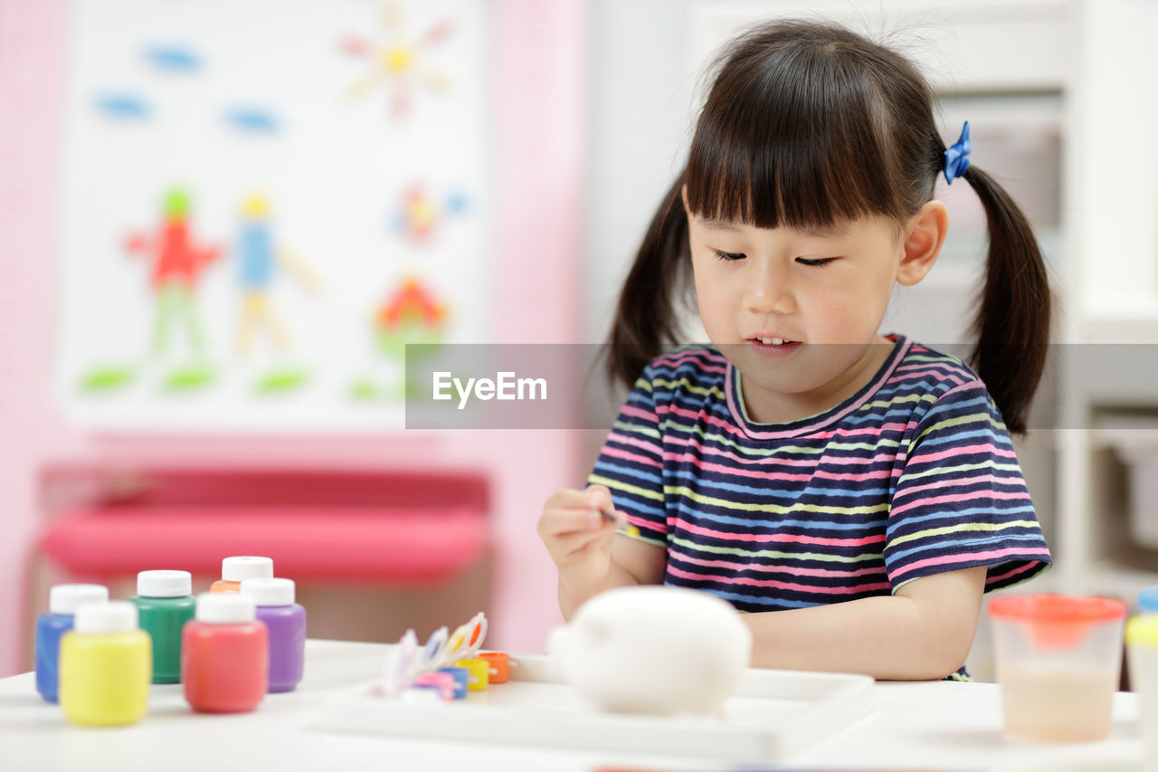 Young girl decorating handmade craft for home schooling