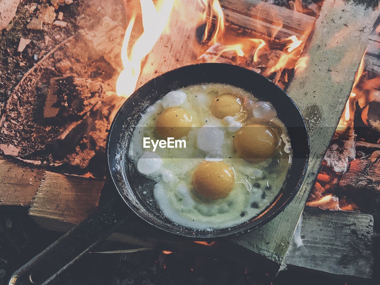 High angle view of eggs in cooking pan over burning wood