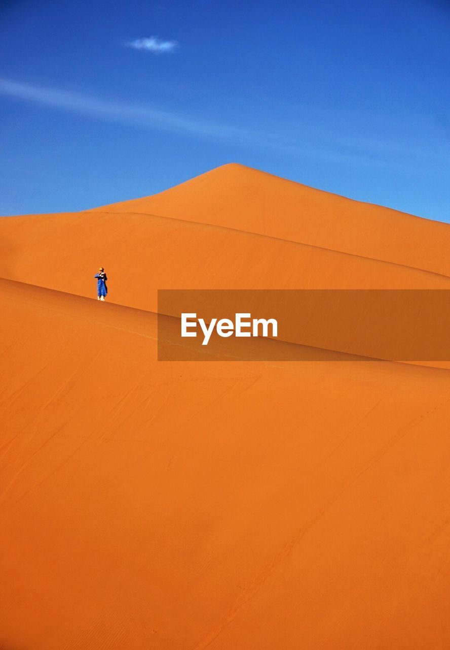 Distant view of person standing at desert