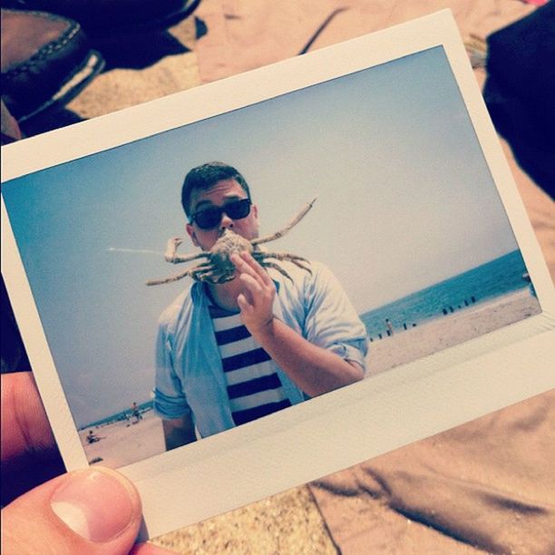 Hand holding instant photo picture of man with crab