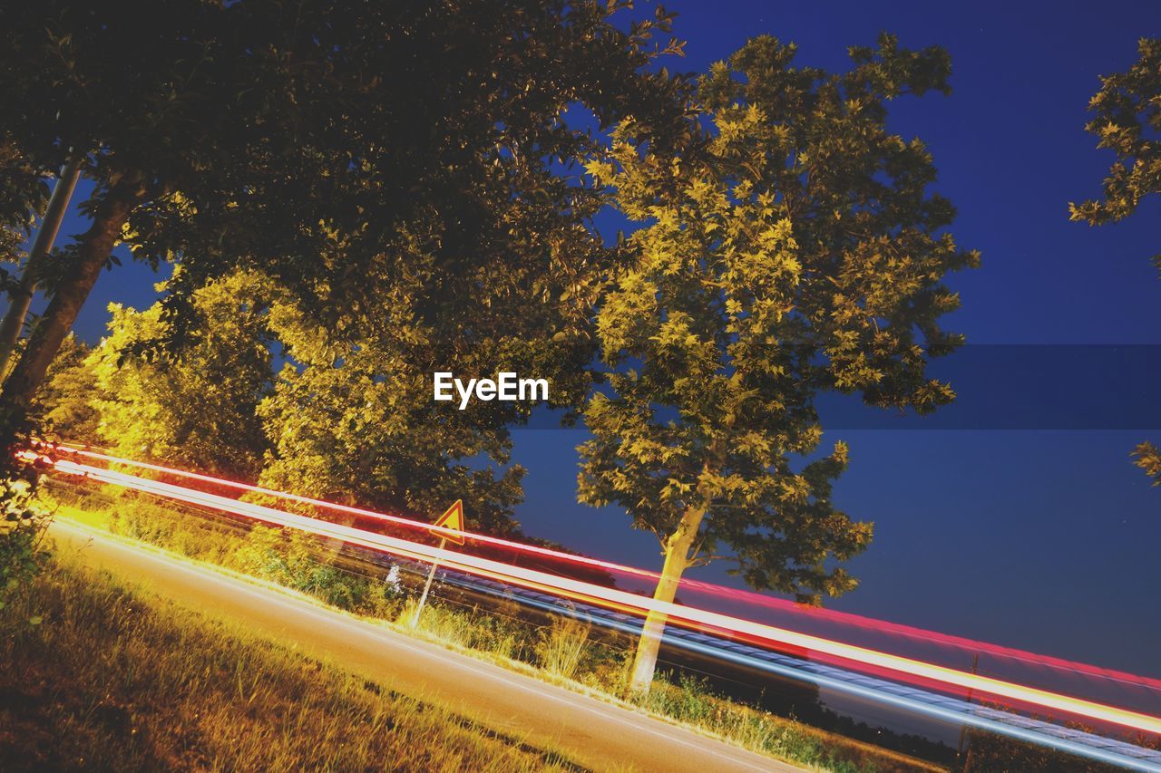 Light trails on road against sky