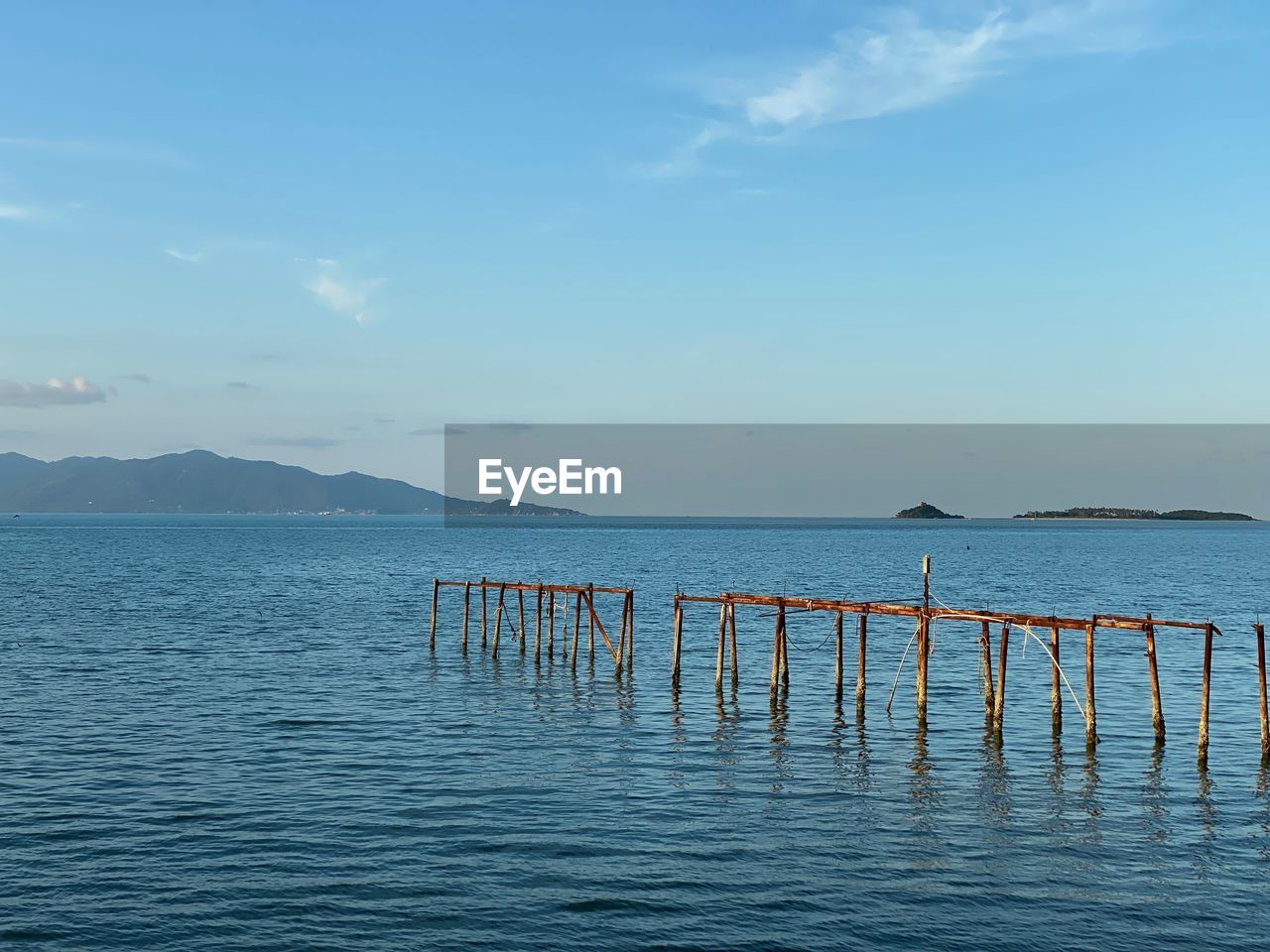 water, sky, horizon, sea, ocean, scenics - nature, beauty in nature, shore, tranquility, tranquil scene, nature, cloud, body of water, no people, bay, coast, blue, day, horizon over water, idyllic, wave, pier, vacation, beach, outdoors, non-urban scene, reflection, wooden post, wood, land, waterfront, mountain, post