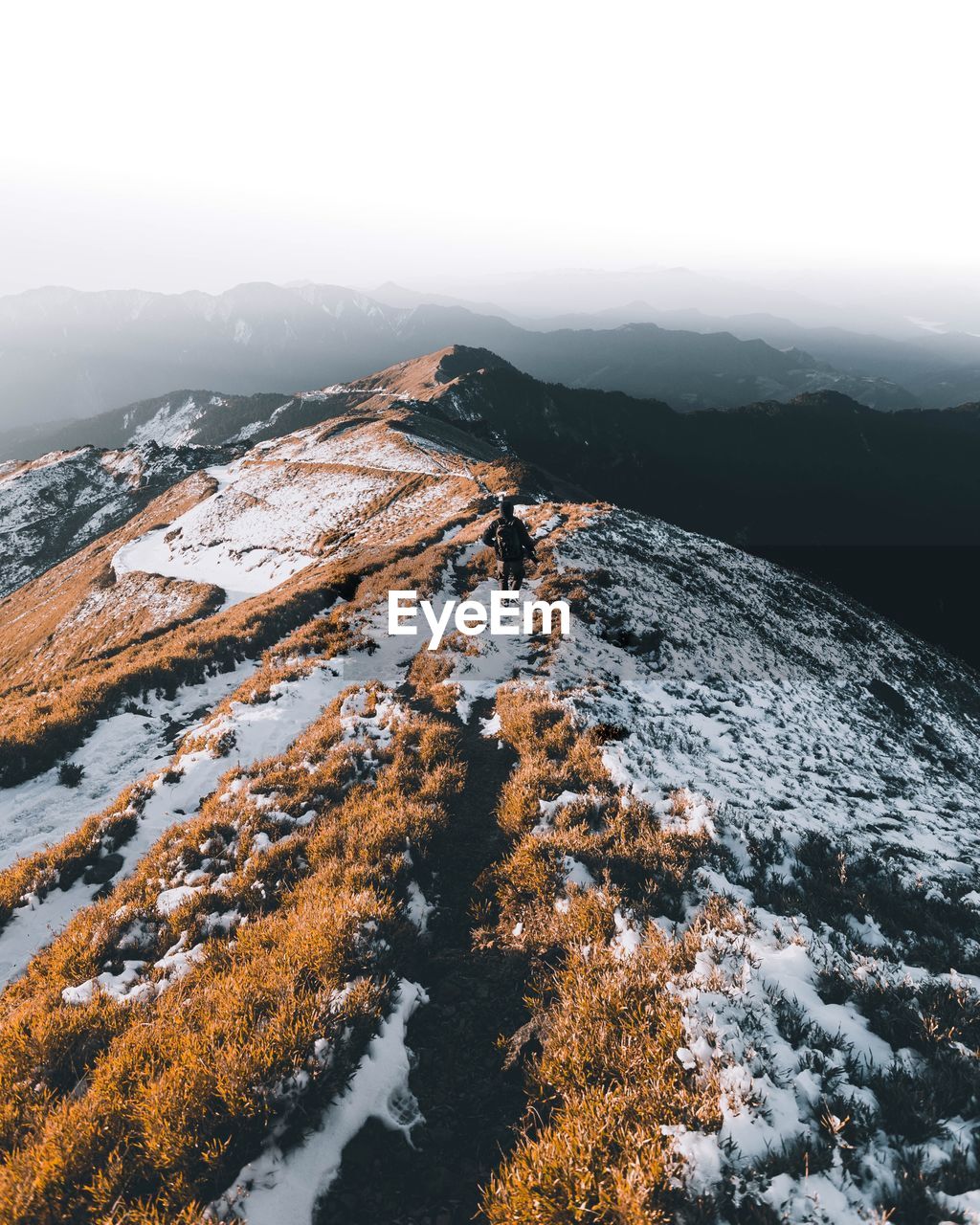 Rear view of hiker with backpack standing on mountain against sky