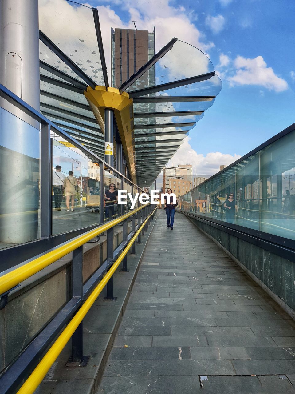 REAR VIEW OF MAN WALKING ON RAILROAD STATION PLATFORM