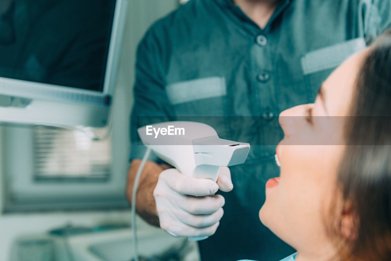 Midsection of dentist examining patient teeth